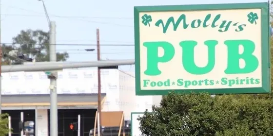 The roadside sign for Molly's Pub in Conroe, reading Food, Sports, Spirits.