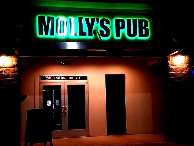 The entrance to Molly's Pub in Tomball at night, under a green neon sign.