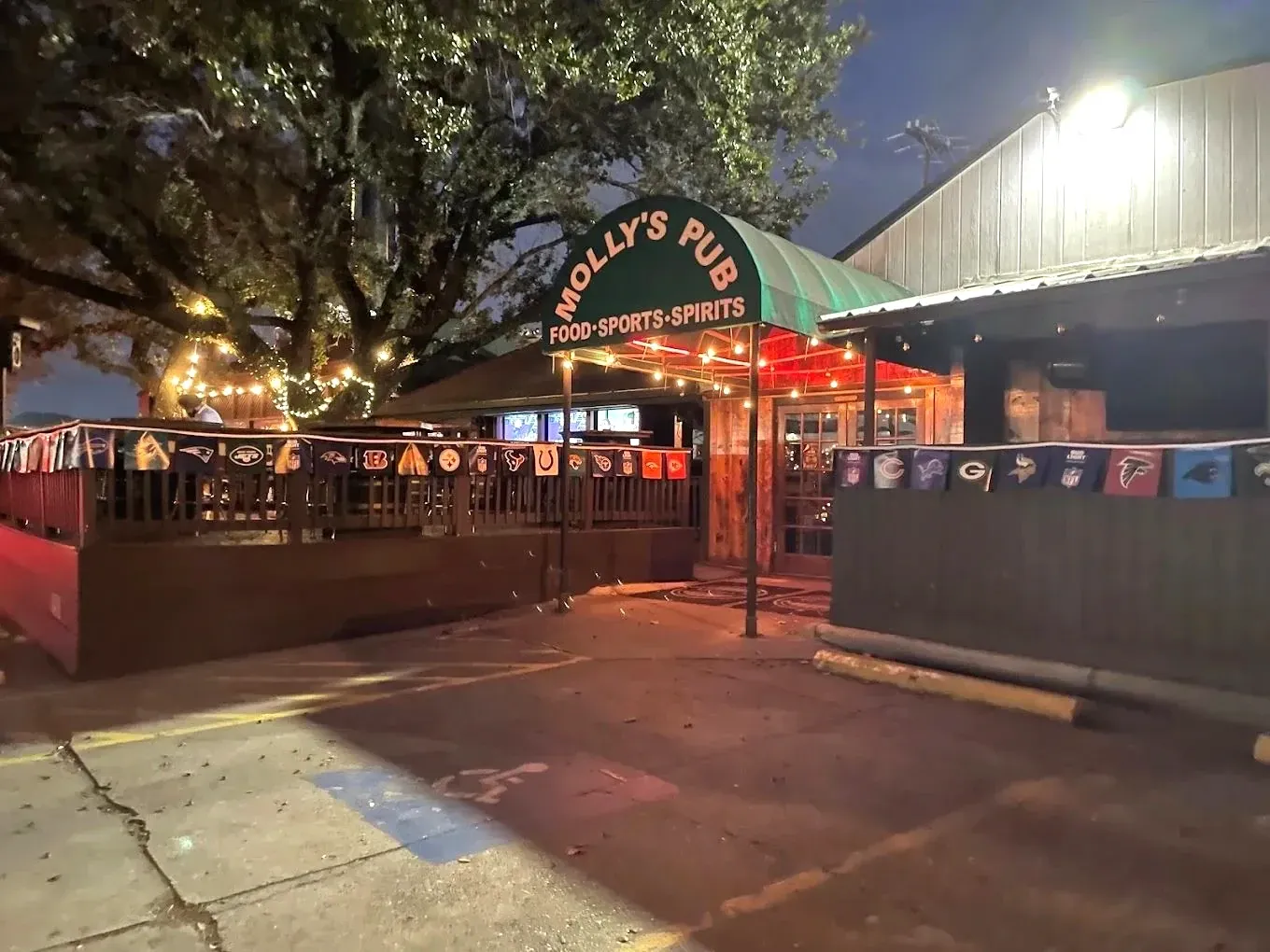 The exterior and patio of Molly's Pub in The Woodlands at night, lit by strings of lights.