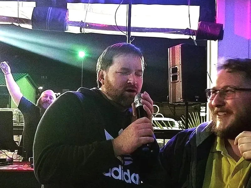 A singer performing on stage with a microphone during a karaoke night.