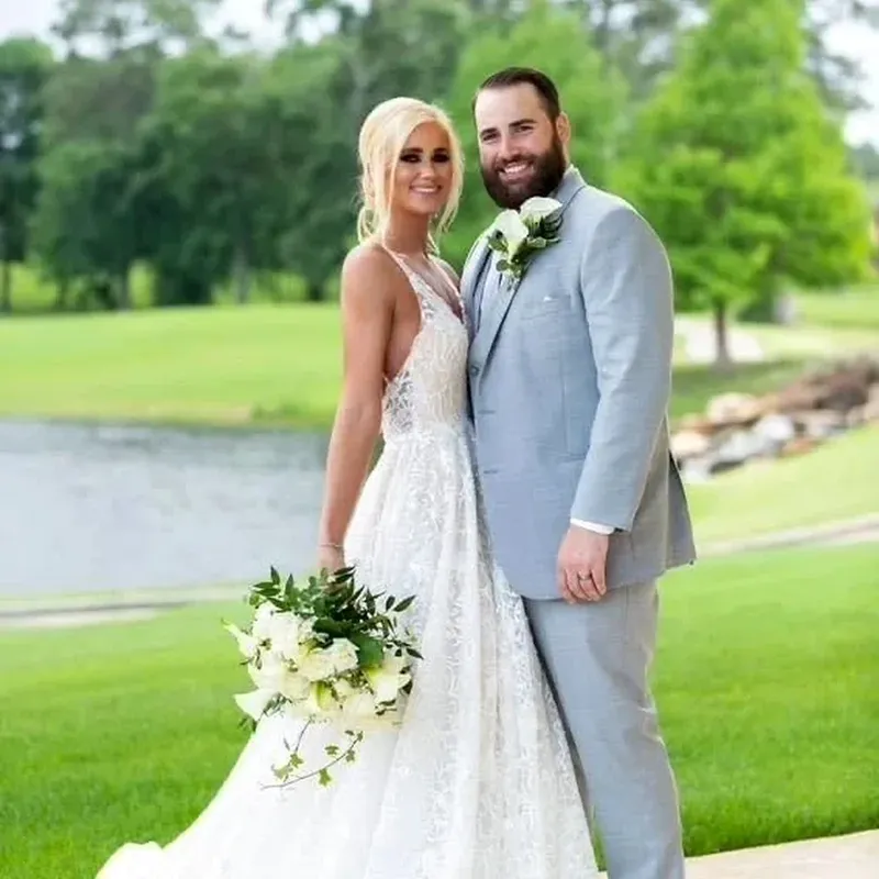 A bride and groom photographed outdoors beside a lake.