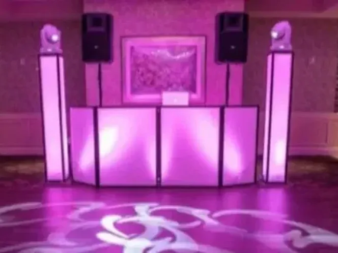 A DJ booth lit in purple with uplighting washing the venue walls.