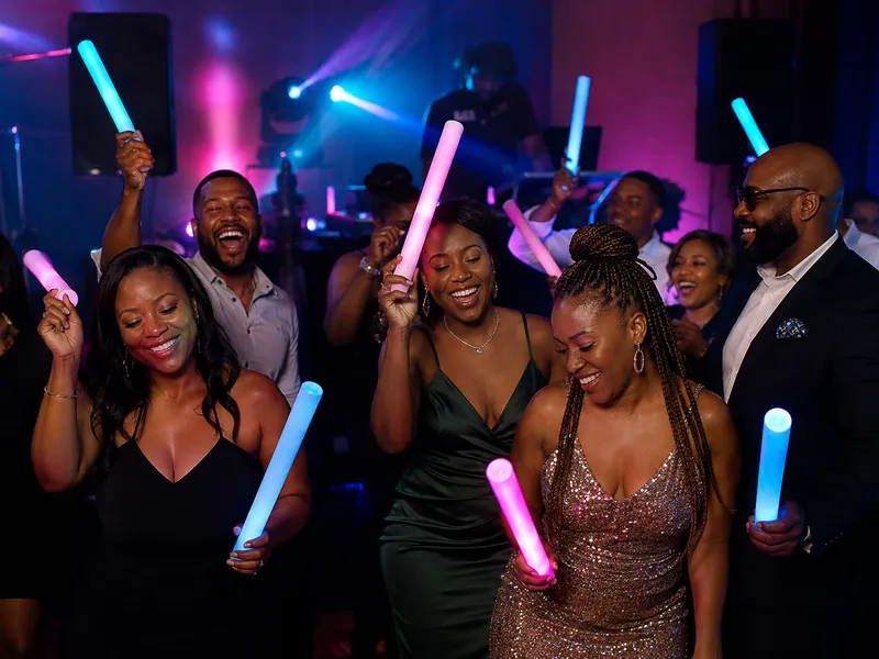 Birthday guests dancing with glowing blue and pink LED foam batons.