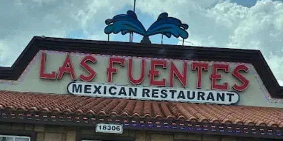 The roof sign of Las Fuentes Mexican Restaurant in red lettering, with the street number 18306 on the wall below it.